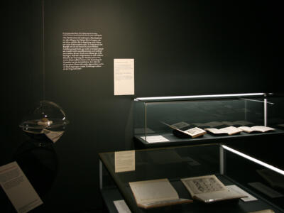 Einblick in einen dunklen Ausstellungsraum mit alten Schriften